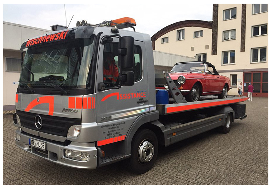 Ein Abschleppwagen hebt ein Elektroauto mithilfe eines Krans von einem Parkplatz